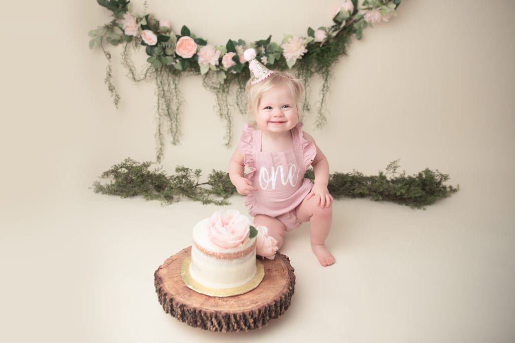 One year old girl celebrates her first birthday with a floral themed smash cake photo shoot.