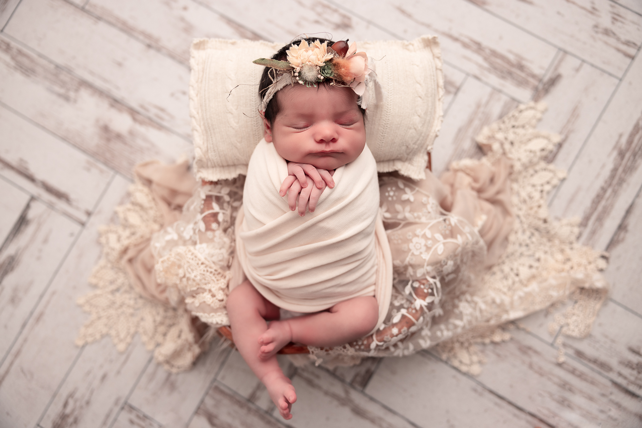 Baby wrapped in netural in a prop and floral headband