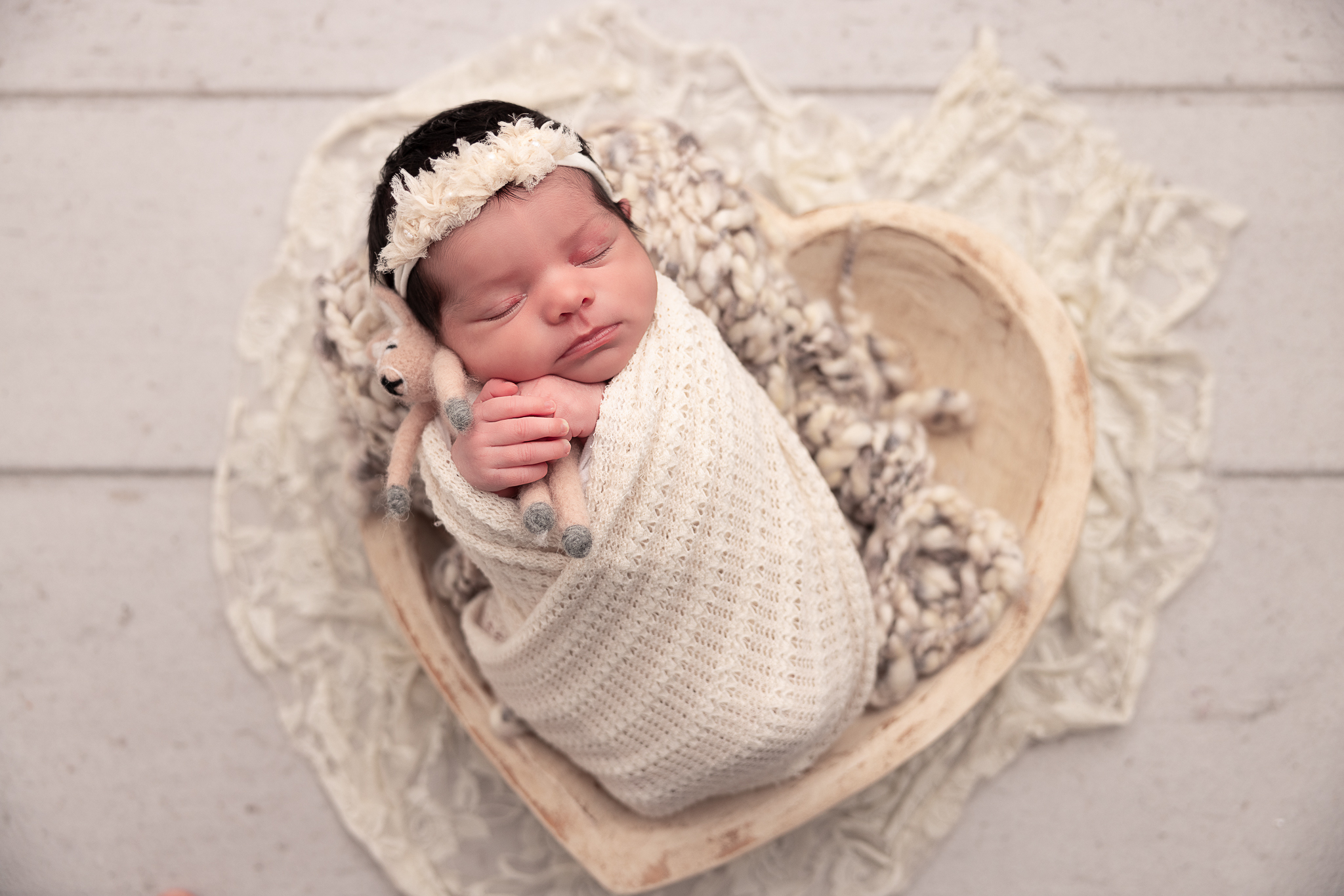 Baby wrapped in neturals in a heart shaped prop