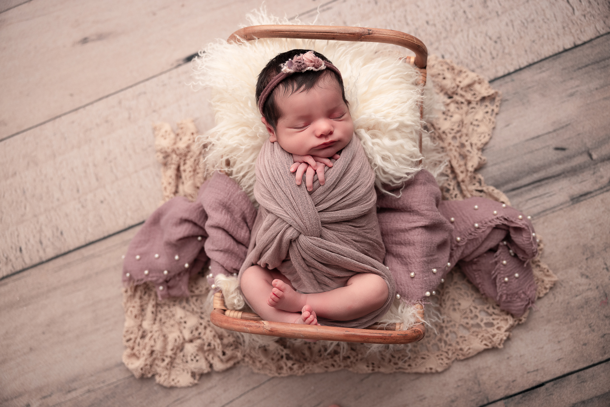 Baby in a bed wrapped in purples