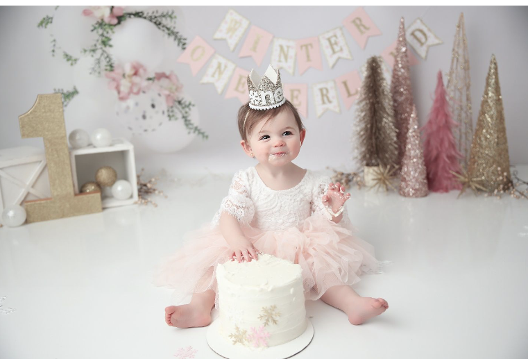 Little baby girl in pink dress smashing white cake