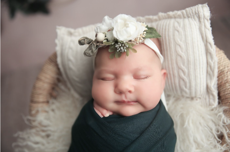 Baby girl in navy blue blanket with white flower headband