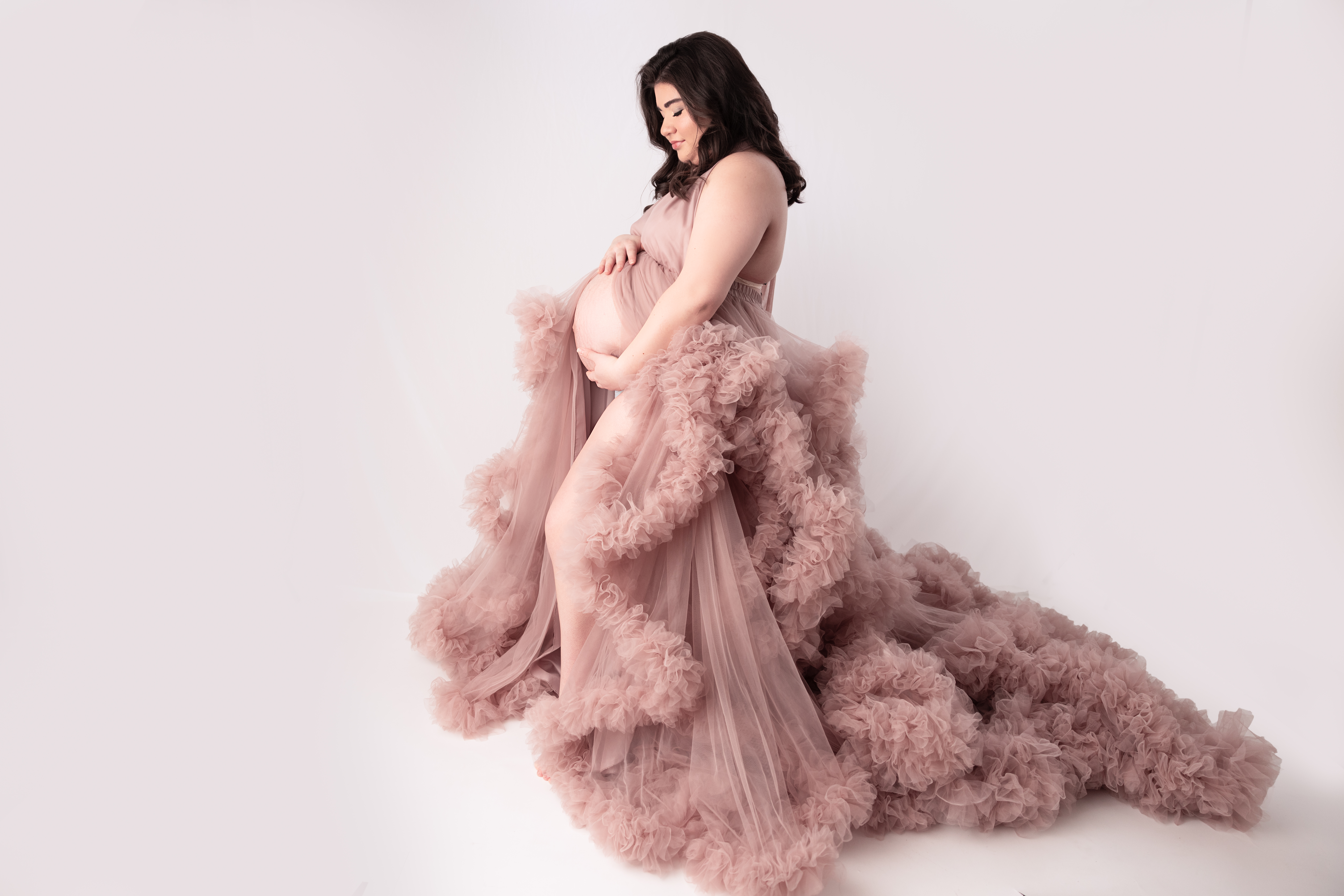 Side Profile of Woman Wearing a Pink Boutique Gown holding he pregnant belly