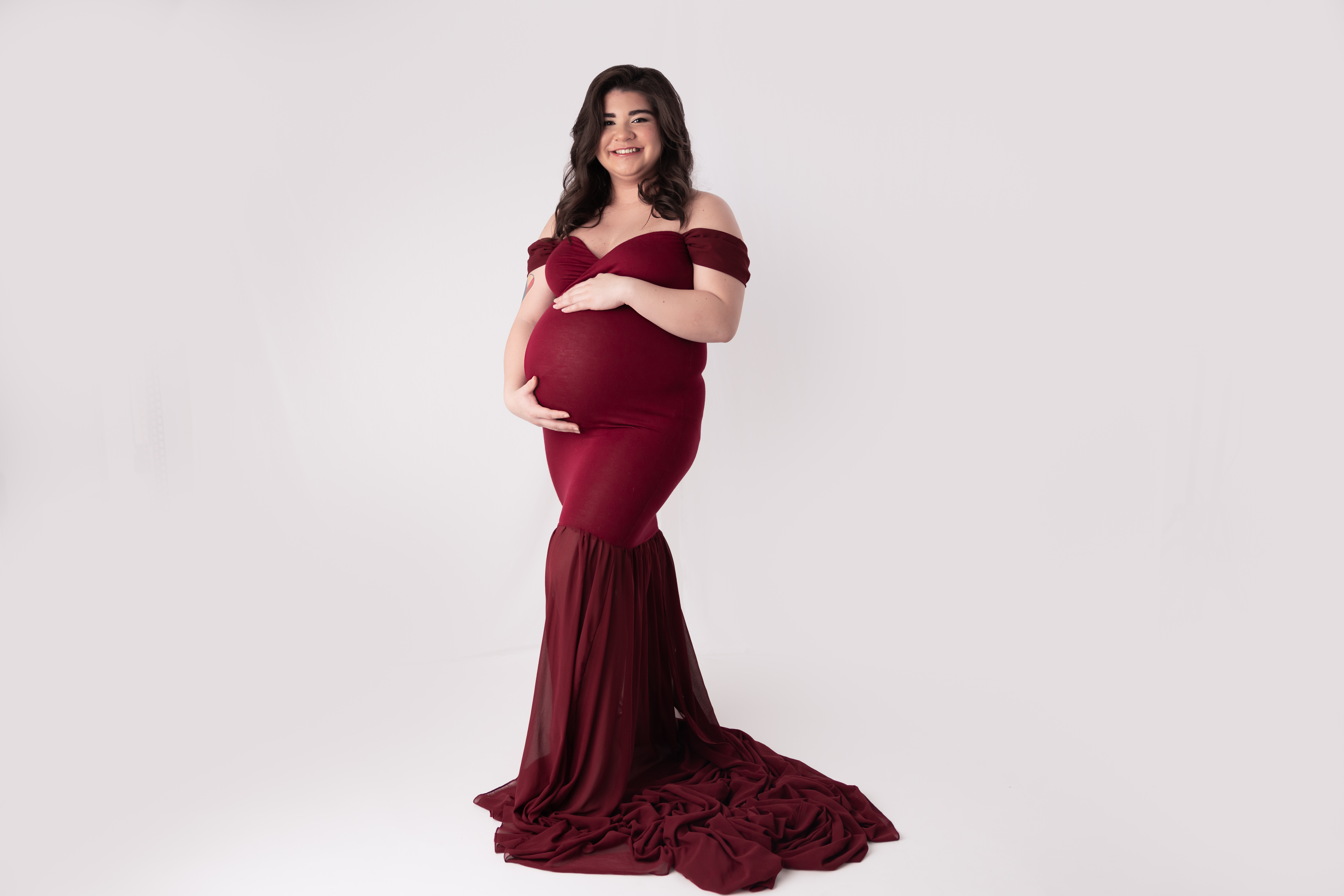 Woman wearing a red gown holding her pregnant belly