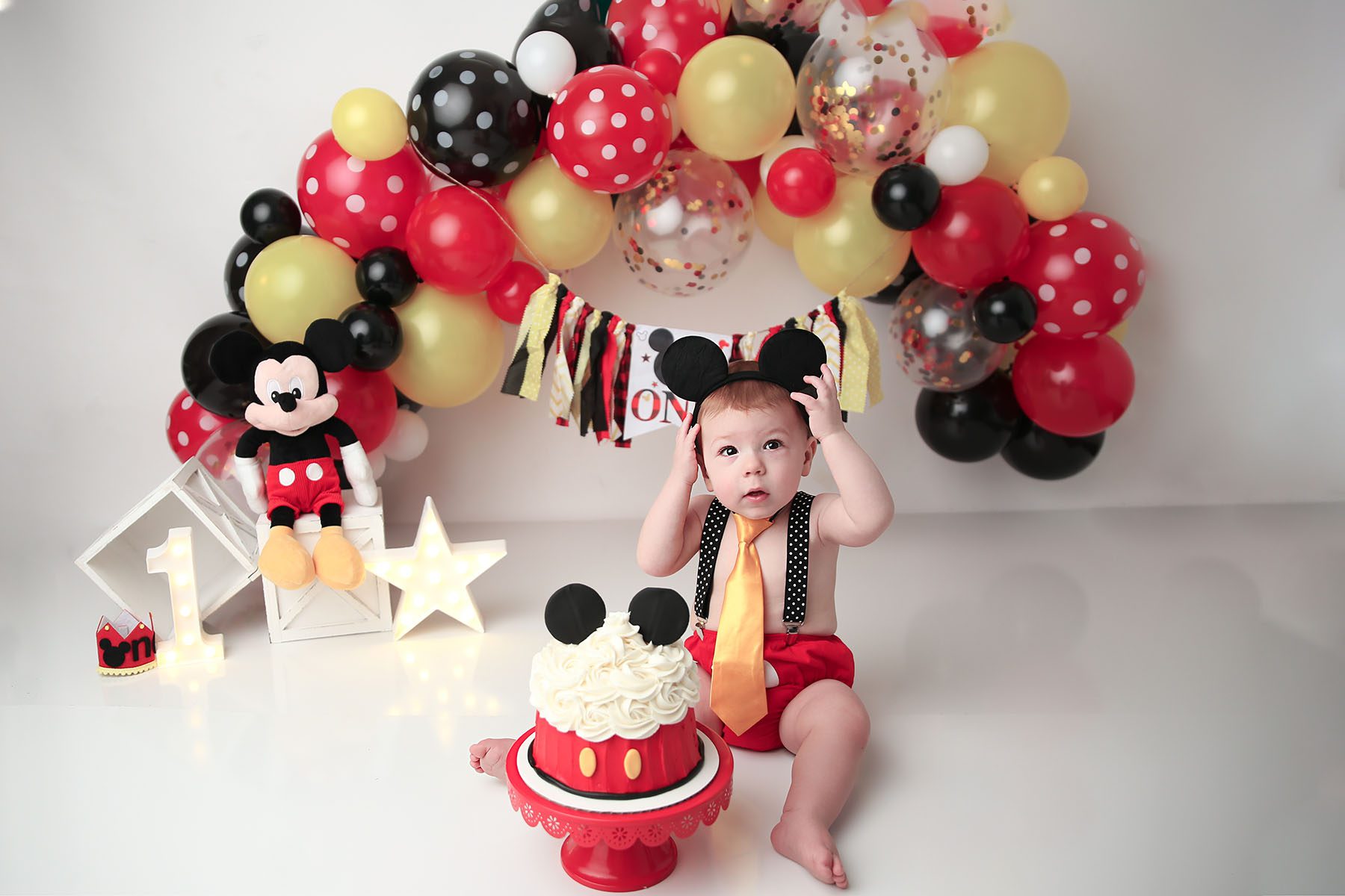 Mickey Mouse themed Cake Smash with baby holding mickey ears