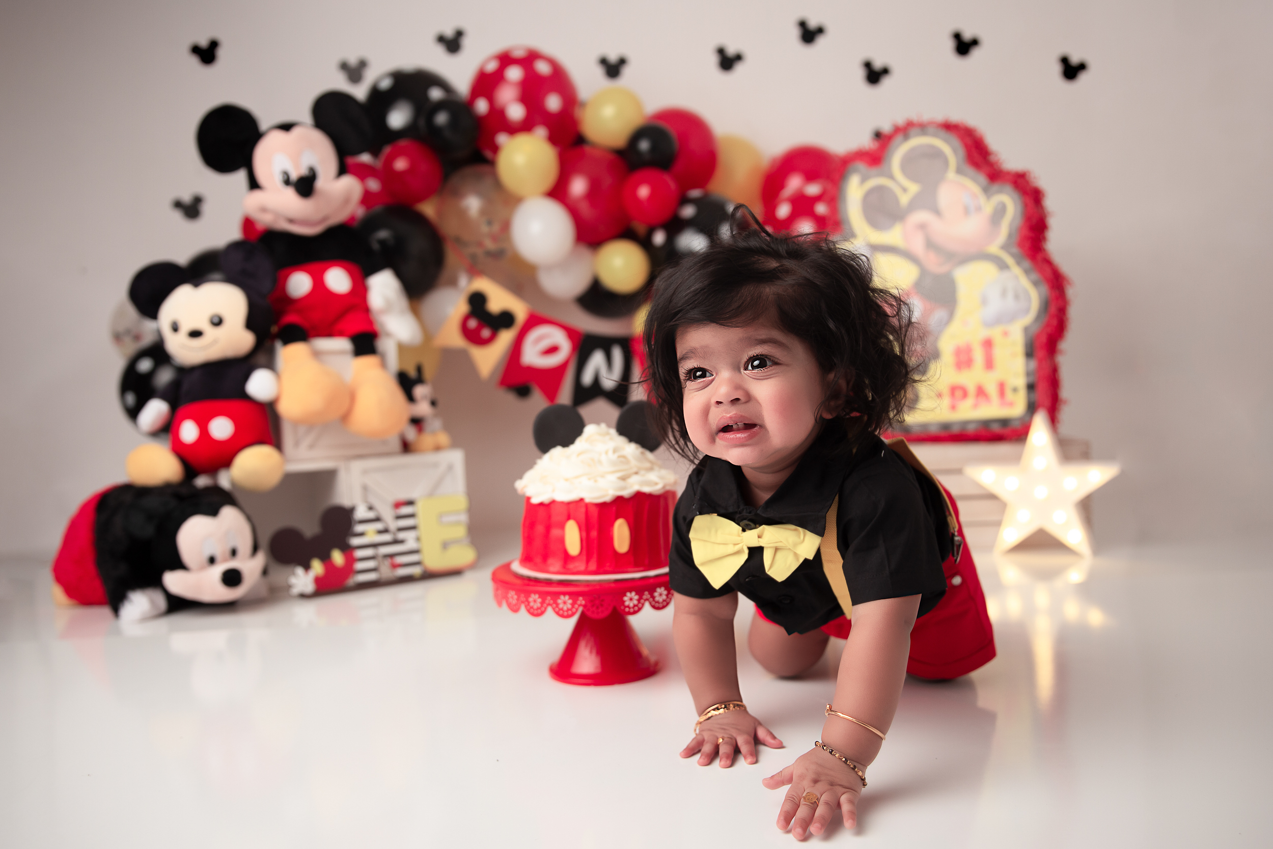Mickey Mouse themed cake smash with a baby crawling and Mickey Mouse backdrop