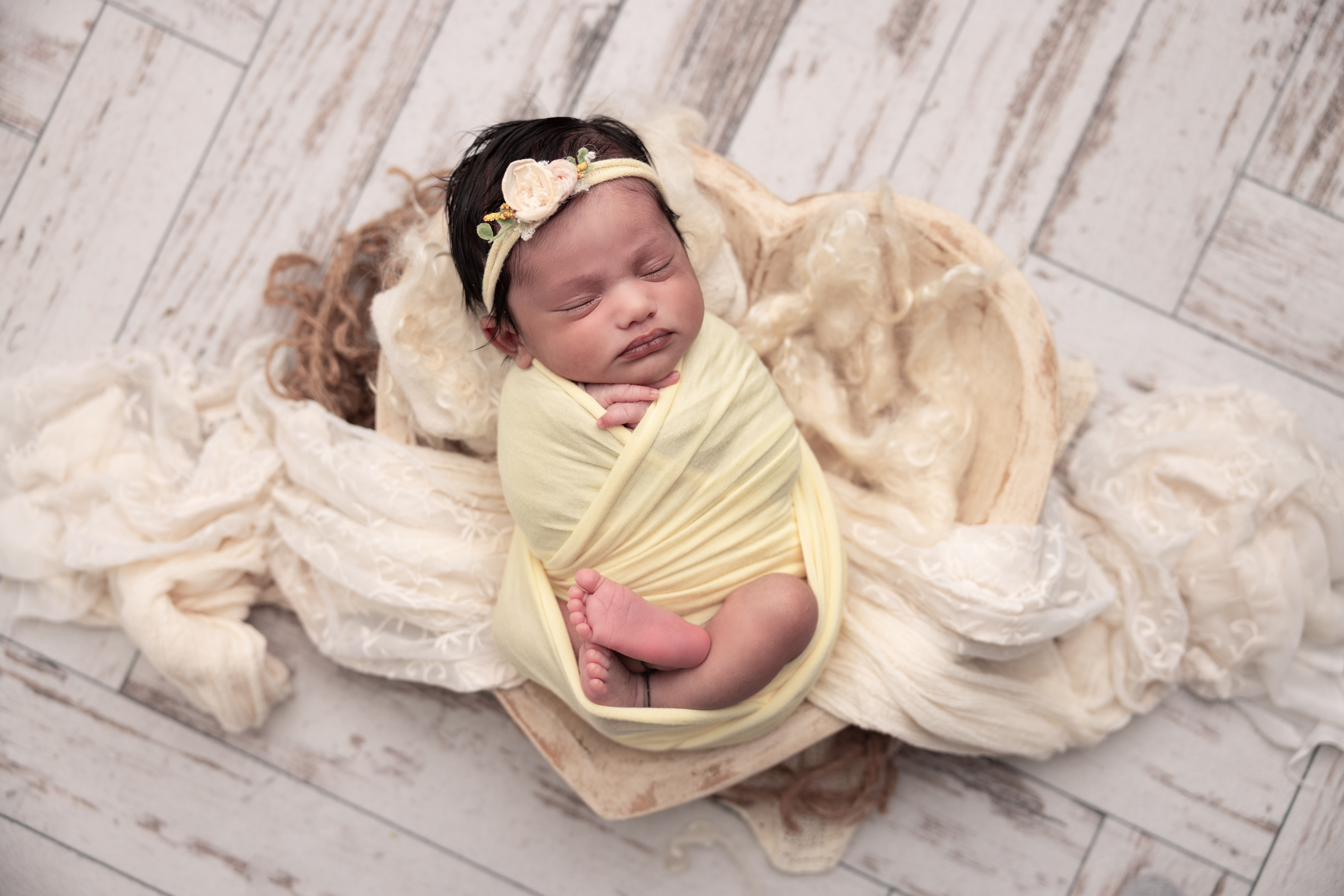 Baby girl in a yellow wrap placed in a heart shape bowl with layers