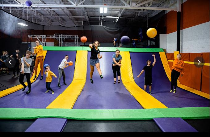 Two kids on a tramploline in a trampoline park throwing balls playing dodgeball