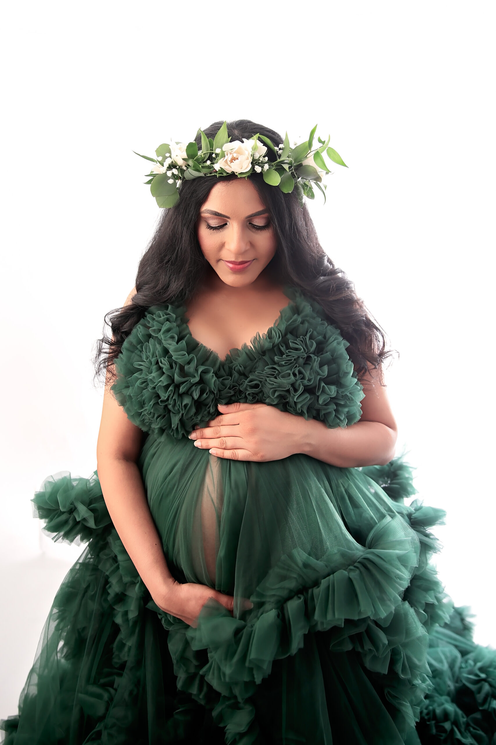 Pregnant Woman with floral crown looing down at her belly
