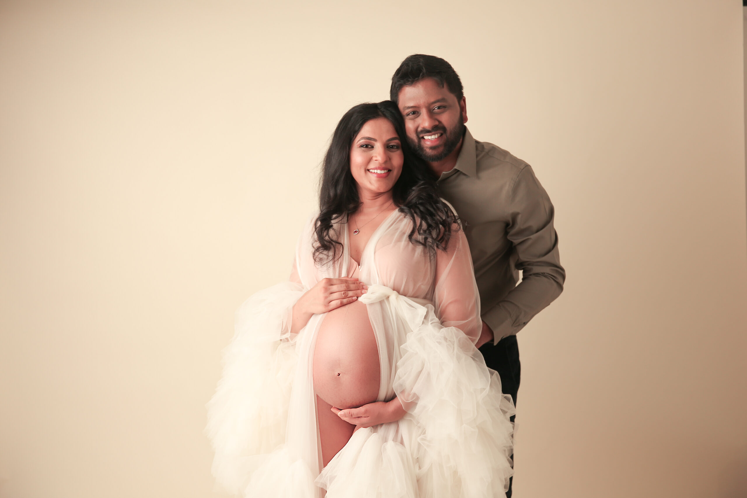Beautiful Couple mom wearing a maternity gown with belly exposed holding her pregnant belly
