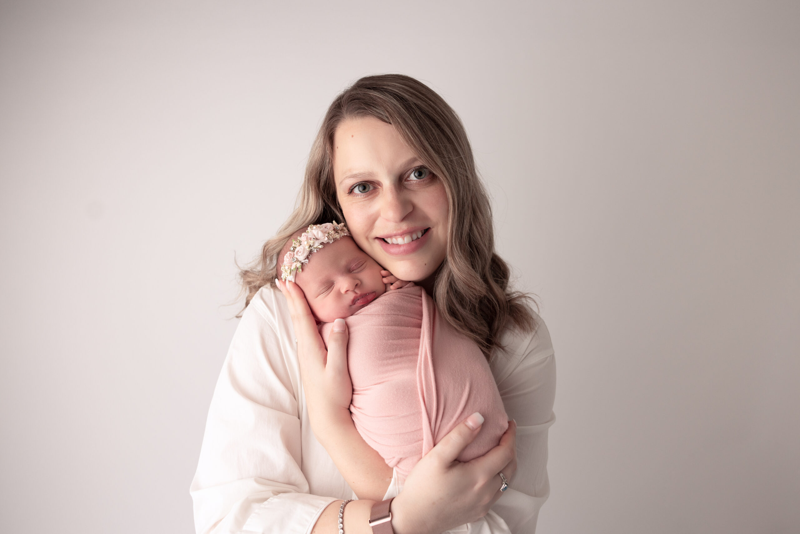 Portrait of Mother holding her baby close to her face while baby is wrapped in pink