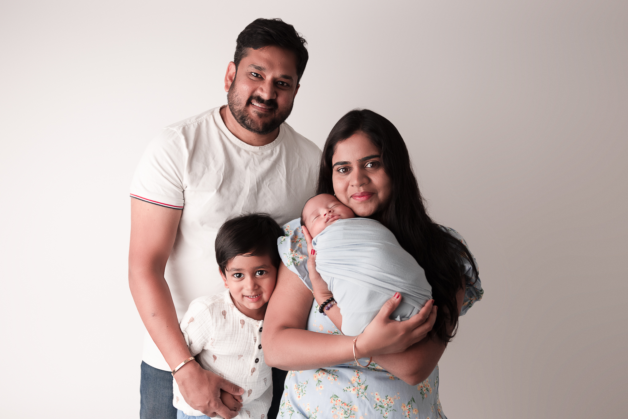 Family Portrait with Mom holding wrapped newborn, Big Brother embracing mom and Dad embracing everyone