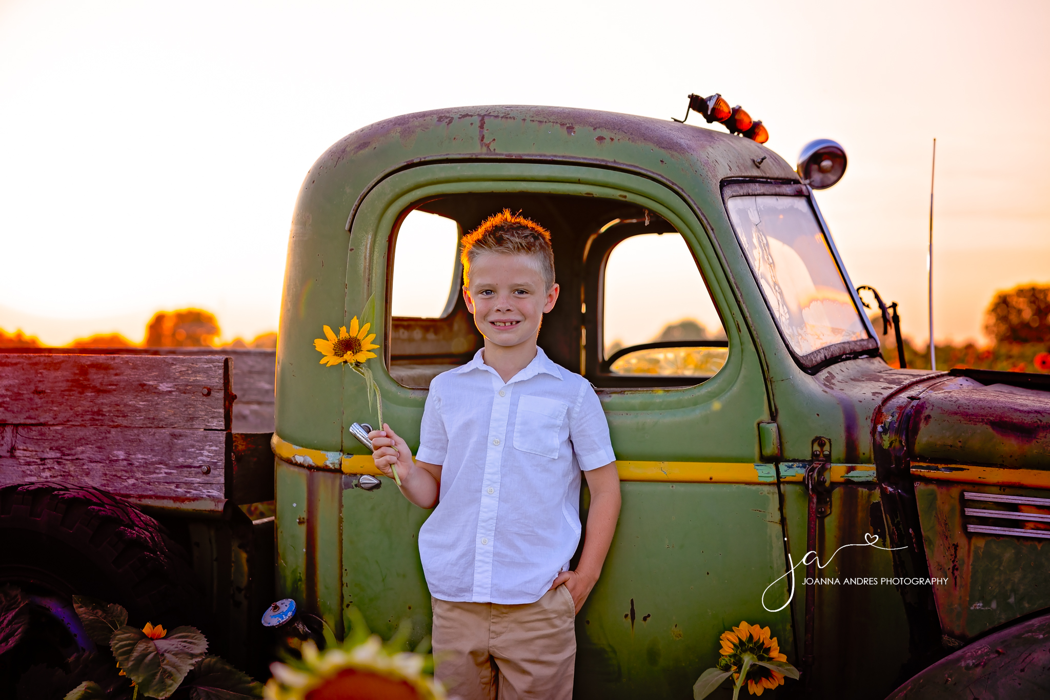 Boy holding a sunflower on a vintage truck