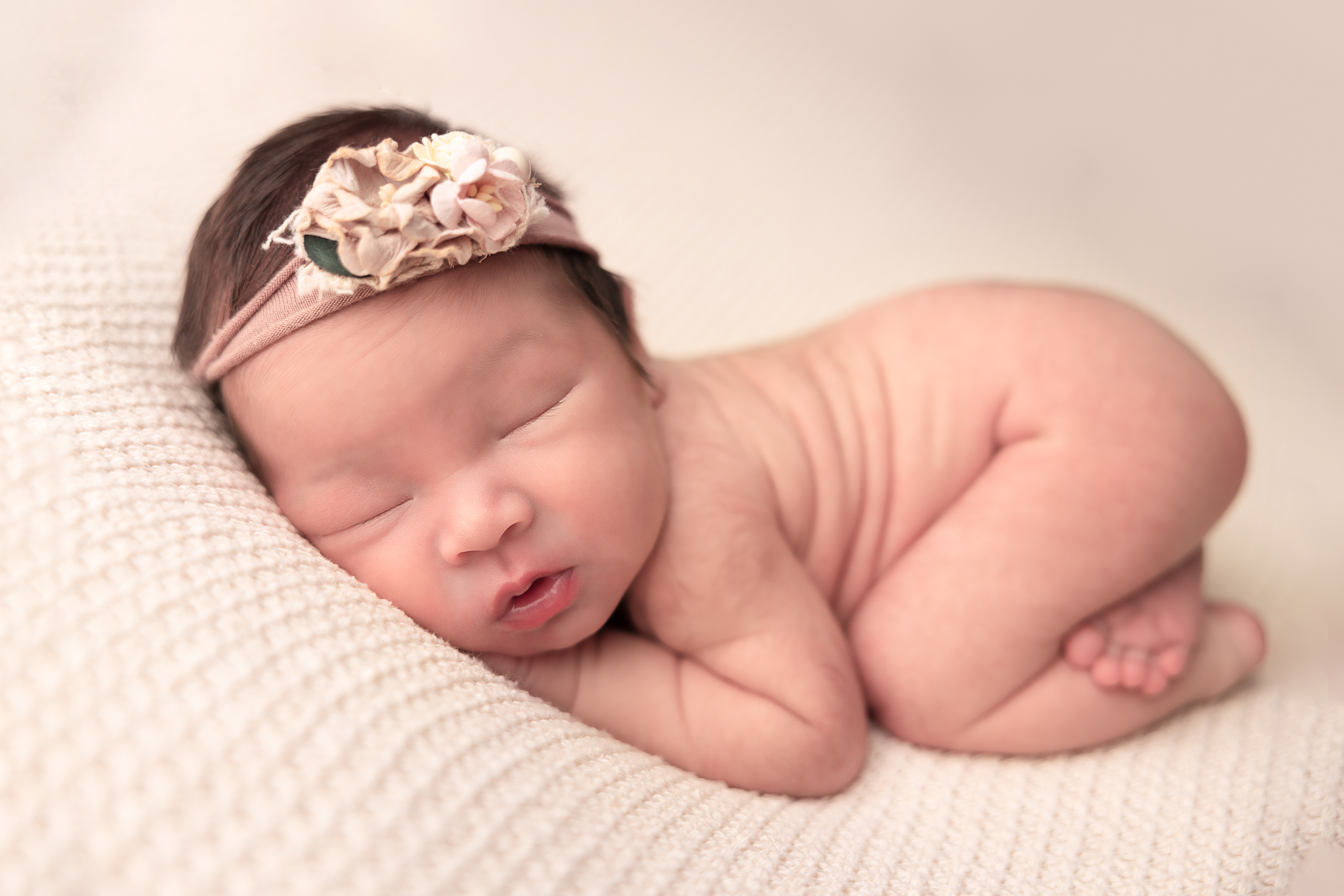 Baby with bum up wearing a pink floral headband