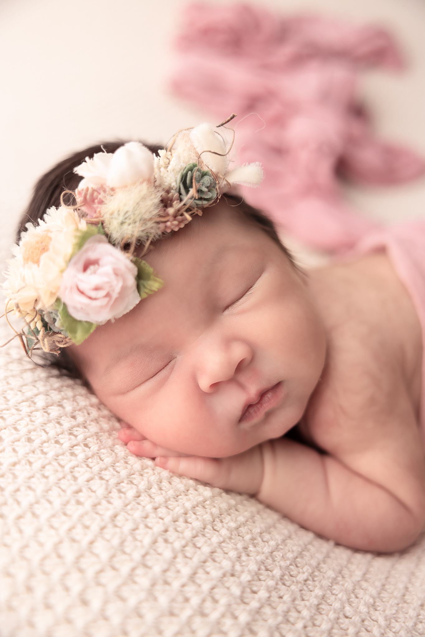 close up of baby's face with floral pink headband