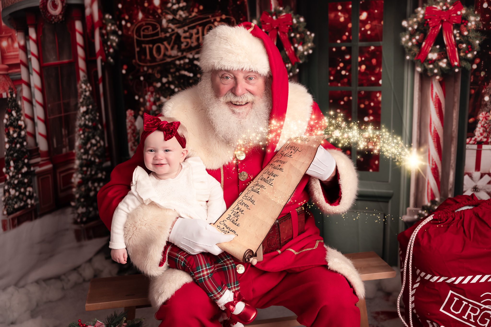 Santa holding a baby with a scroll of the nice list