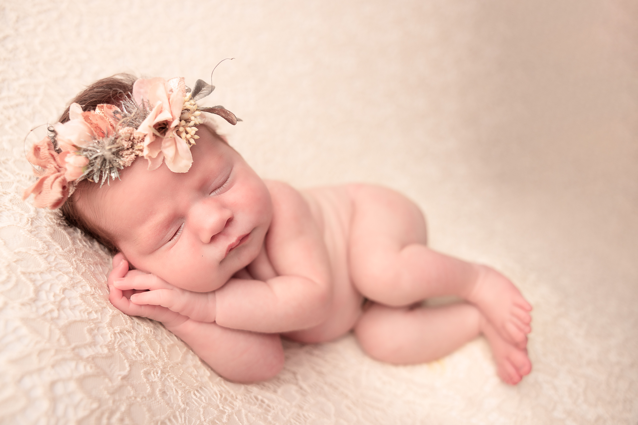 Side Laying Pose of a naked baby wearing a pink floral headband