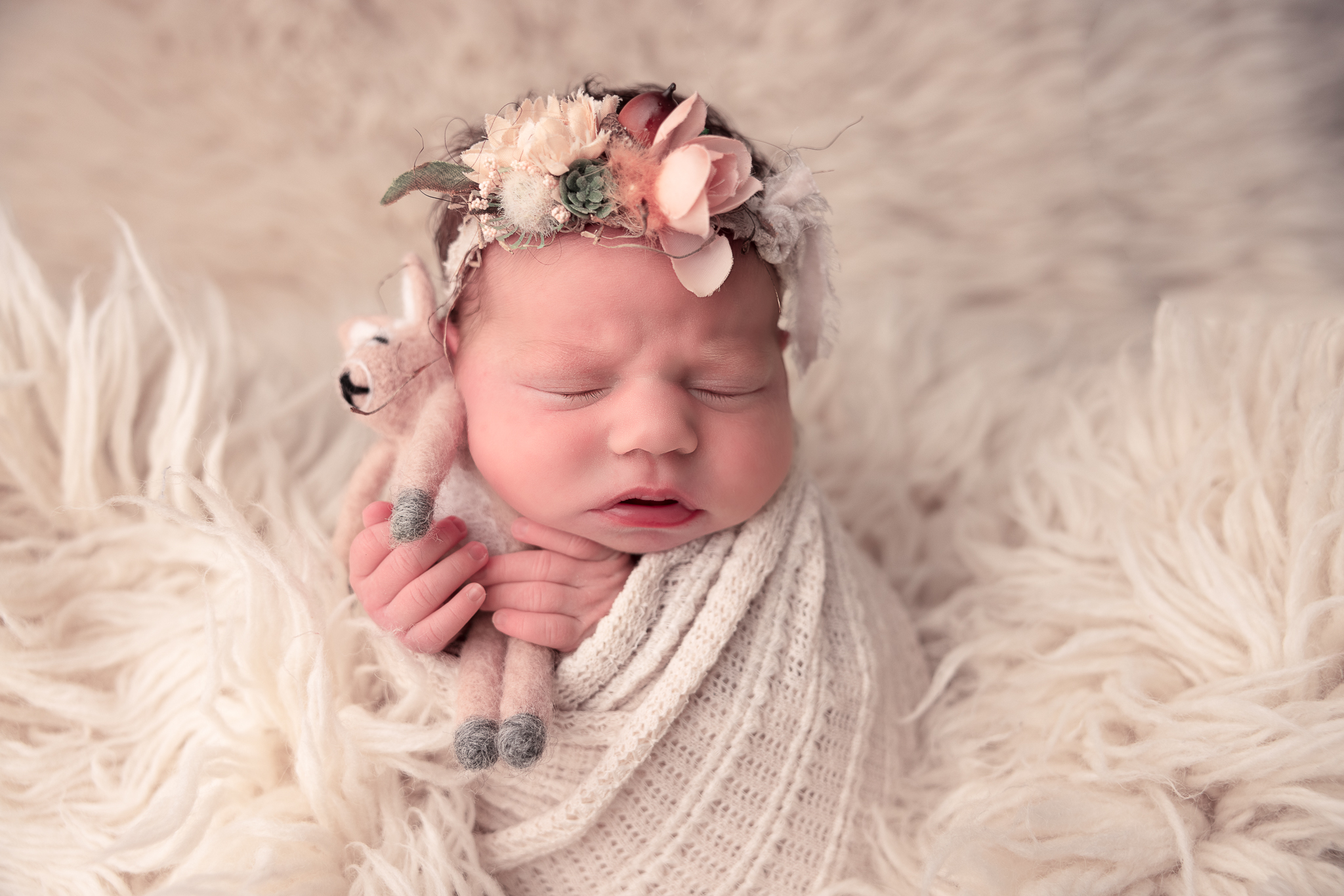 Baby wrapped holding a reindeer lovey