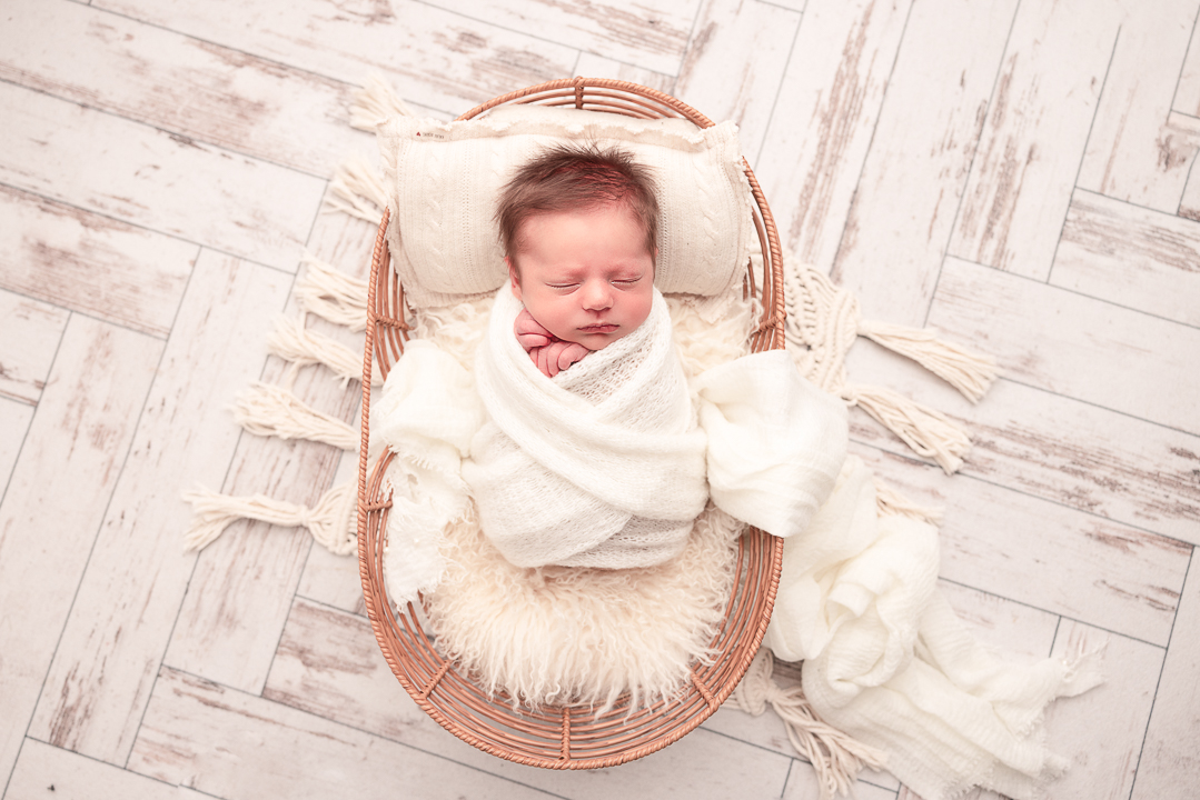 Baby wrapped in white in a basket