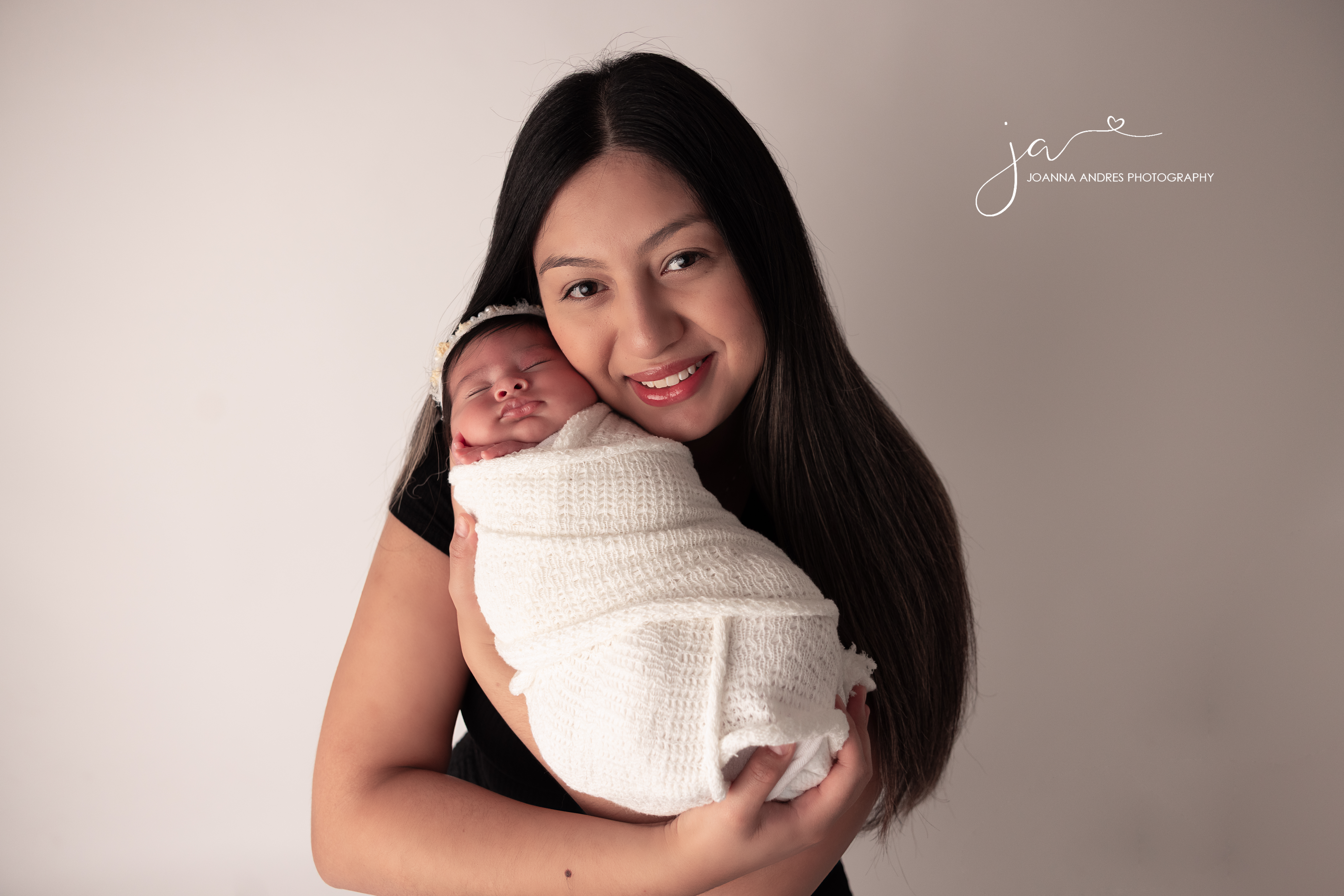 Mom holding her baby and smiling at the camear