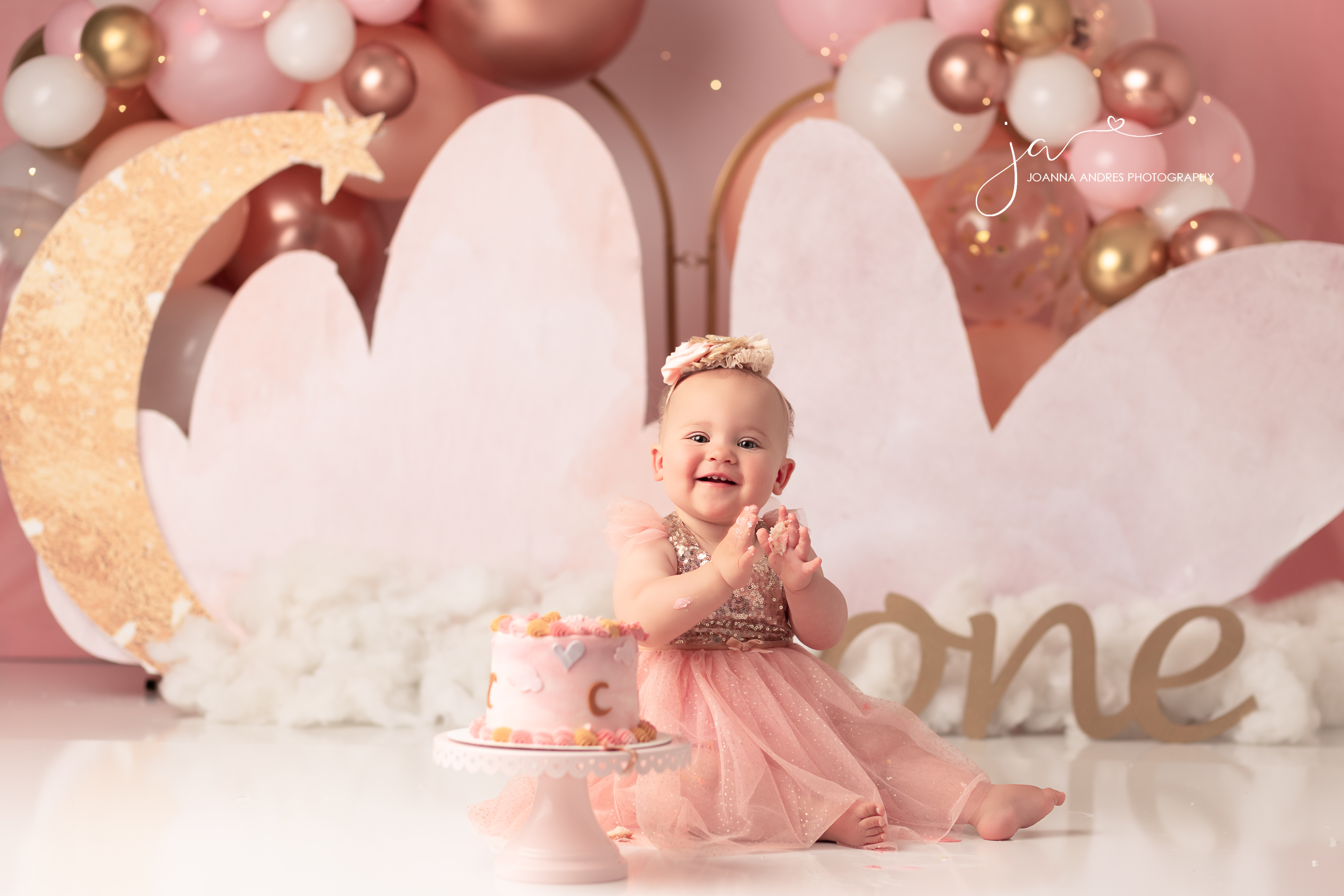 Baby clapping with cake and balloons