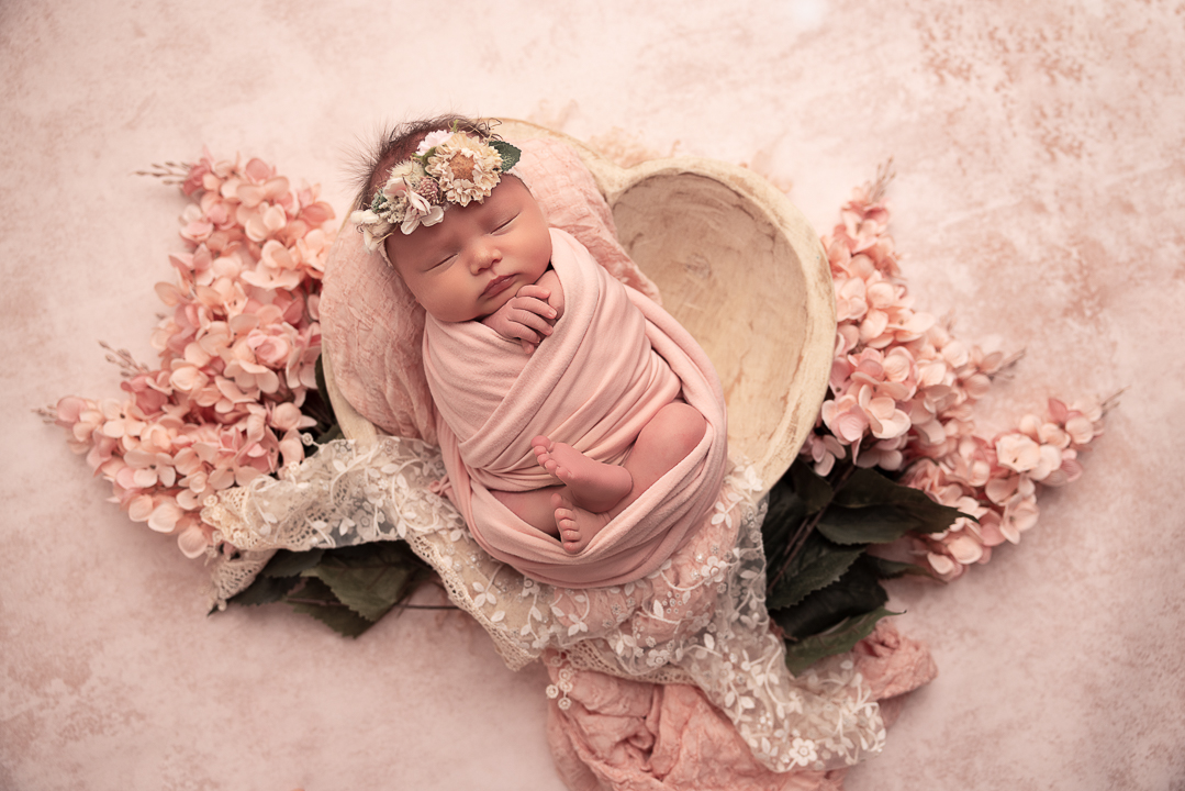 baby girl in a heart shape prop with pink florals