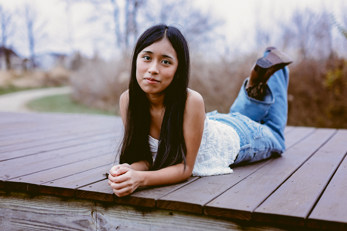 Senior Portraits with kanya laying on her belly on the wood deck at Homestead Park