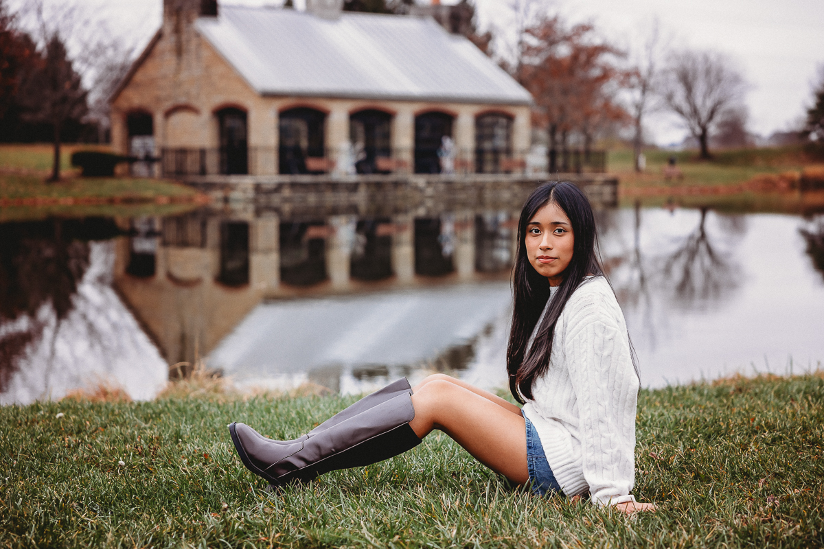 Hilliard Senior Kanya sitting on the grass with the homestead park pond in the backdrop