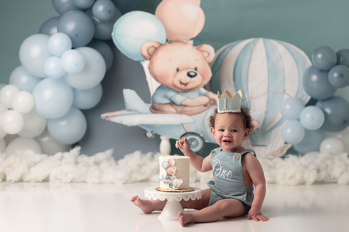 Luxury cake smash photo featuring a custom blue and white airplane and hot air balloon theme for a first birthday session in Columbus, Ohio