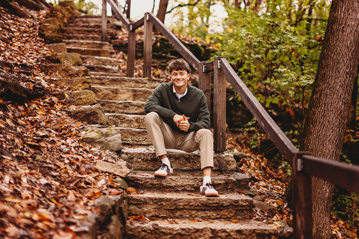 senior pictures of boy sitting on beautiful natural stone stairs at quarry trails park