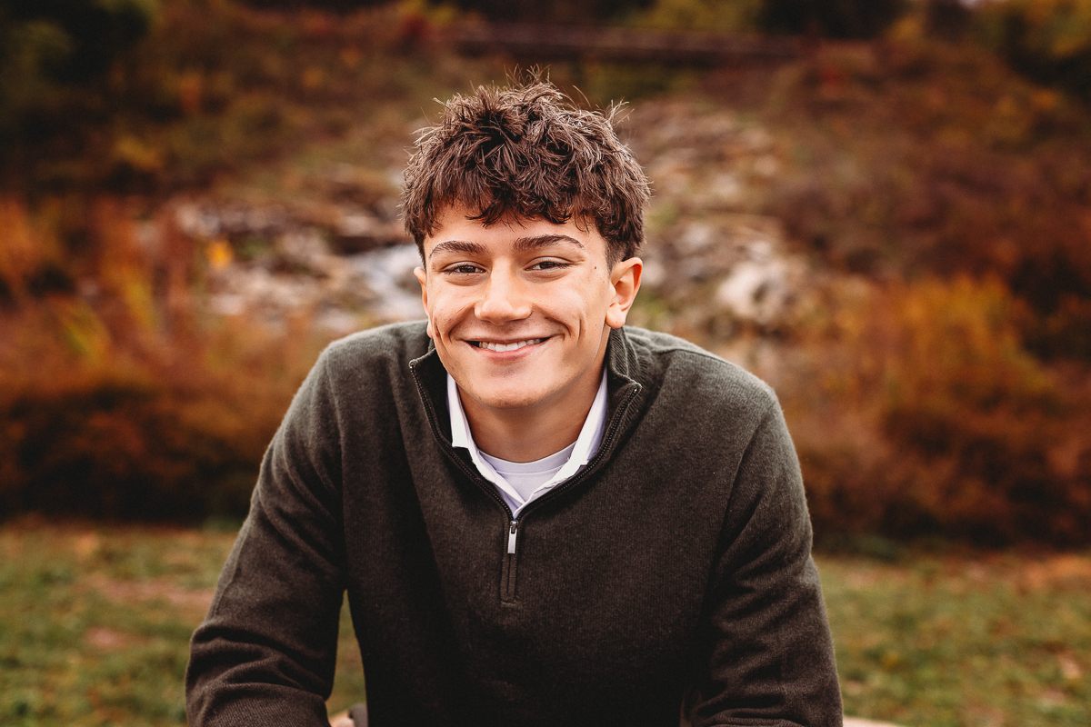Senior pictures of boy smiling with quarry trails park as backdrop