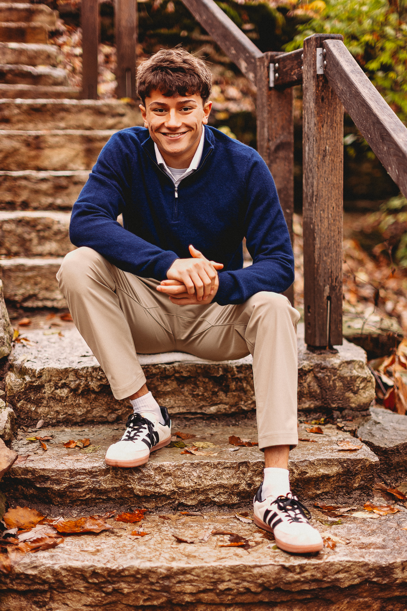 senior boy sitting on quarry stone at quarry trails park