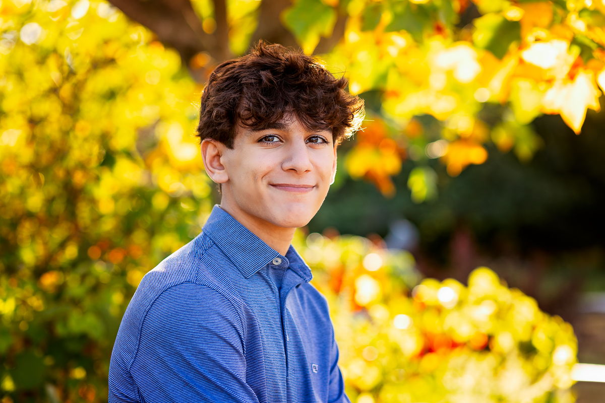 senior portrait with fall leaves in backdrop