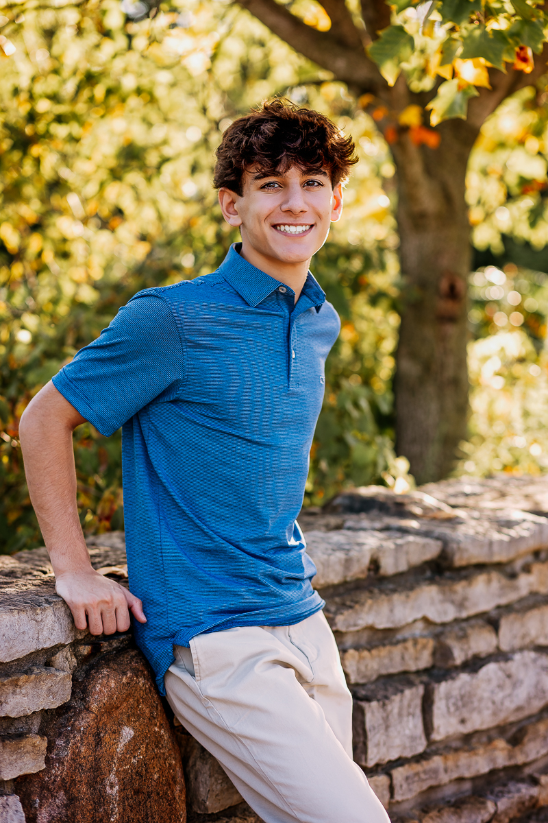 senior portrait leaning against stone wall