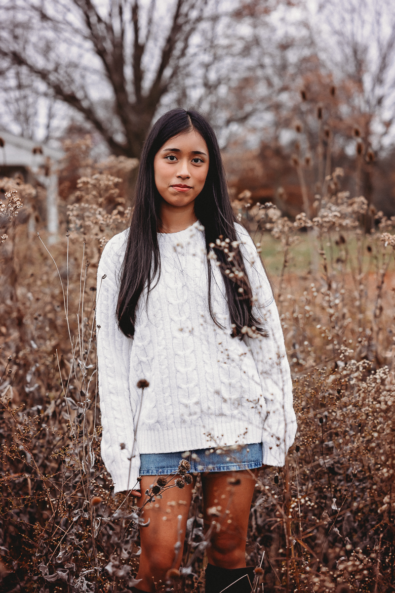 Kanya posing by the dried wallflowers at homeastead park for her senior pictures in hilliard