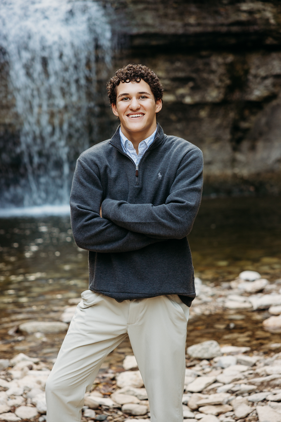 senior high school boy arms crossed and backdrop is waterfall at quarry trails