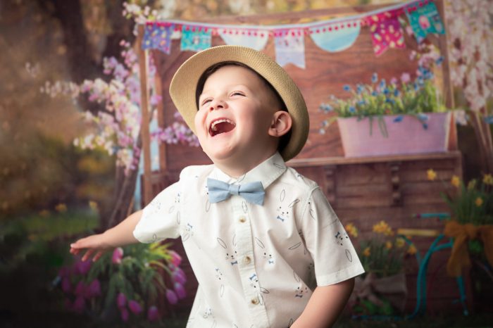 Laughing child with sunhat during picnic themed photoshoot.